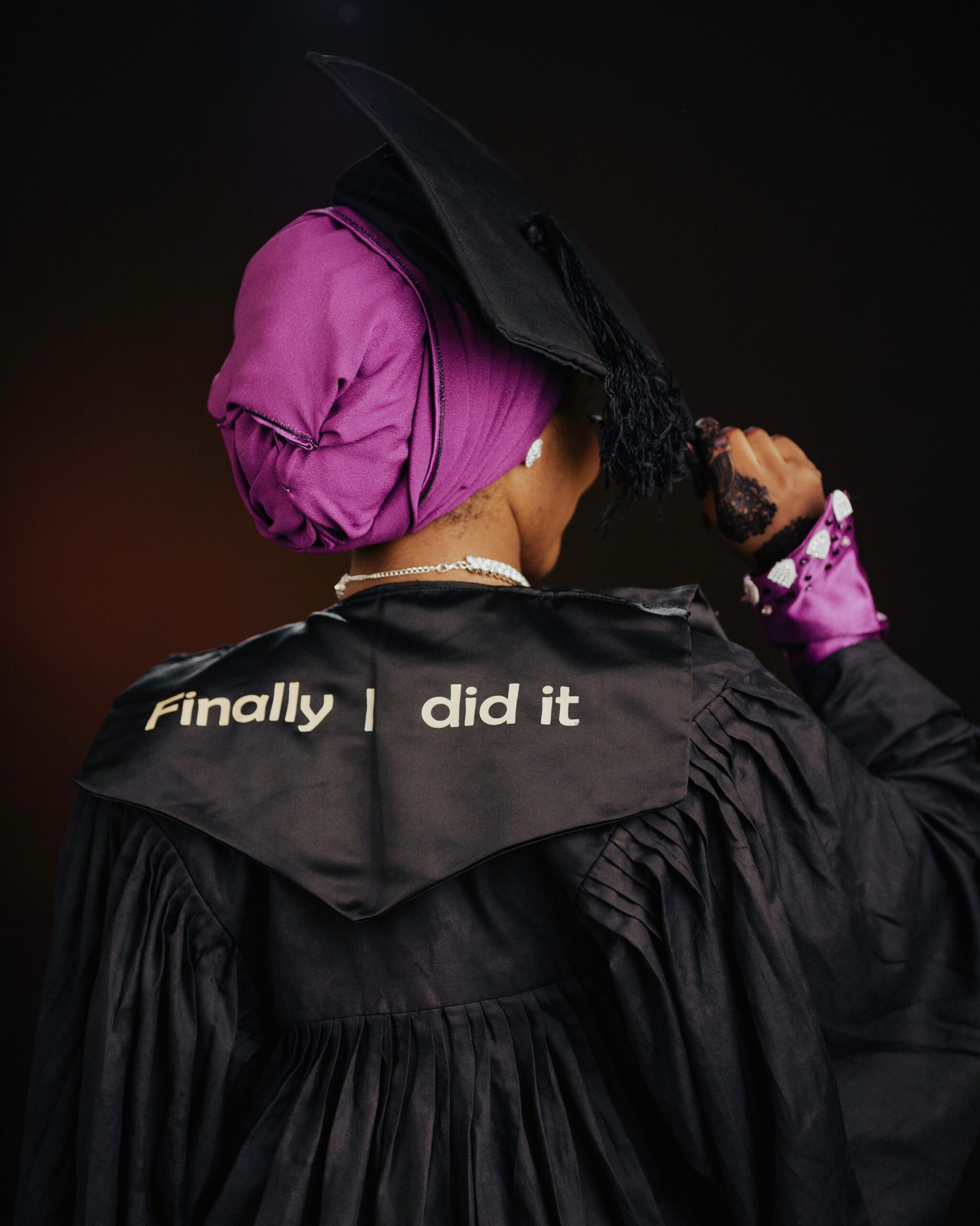 Back view of a female graduate in cap and gown celebrating her success with a message.